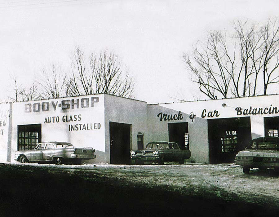 Vintage auto body shop with cars parked outside